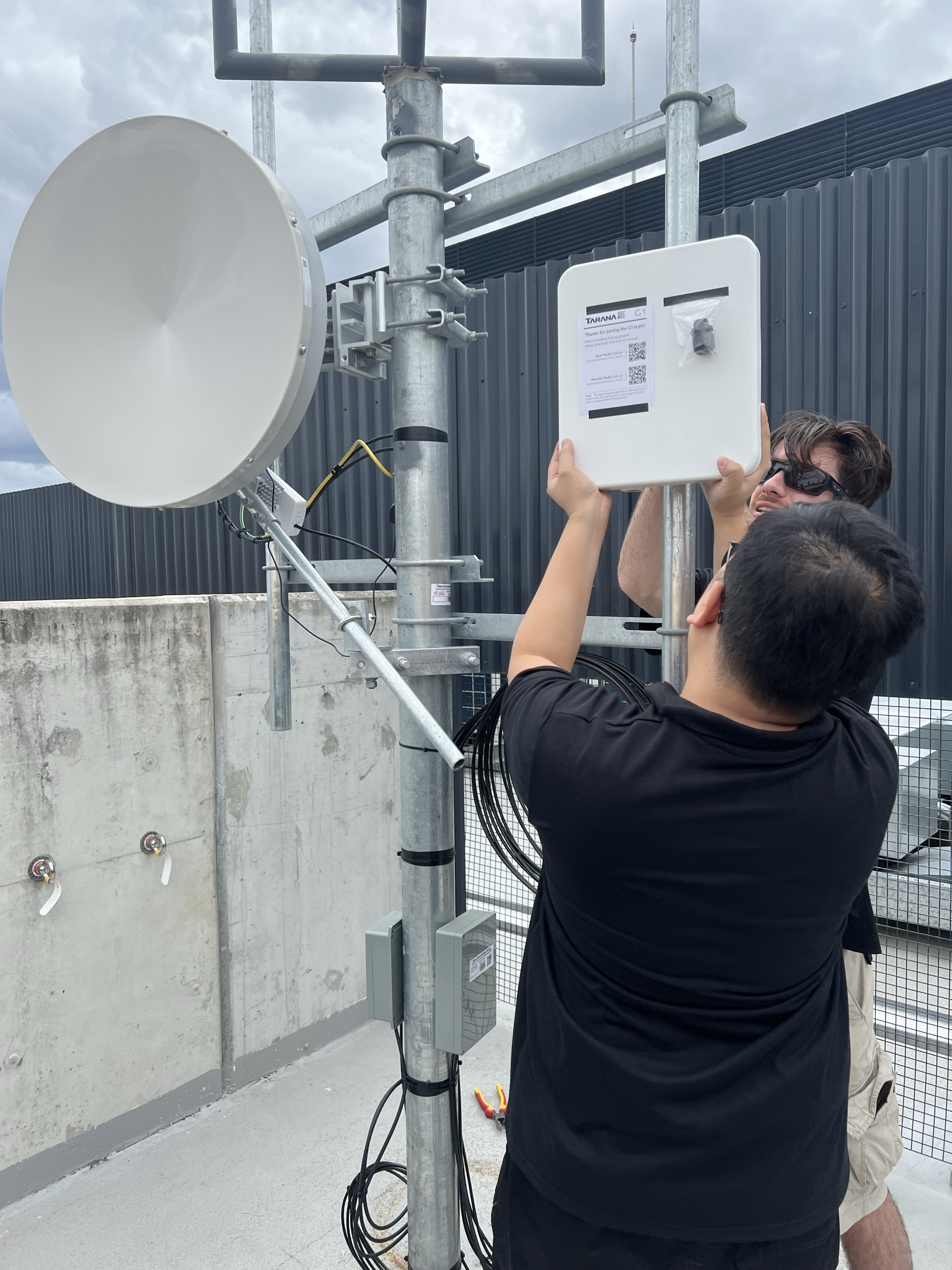 Engineers commissioning Tarana fixed wireless equipment on a rooftop