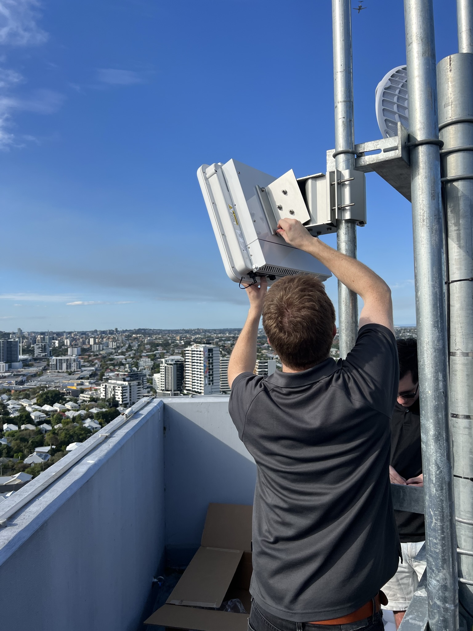 Technician installing Tarana fixed wireless equipment on a rooftop tower